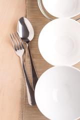 white bowls and silverware on napkin and wood