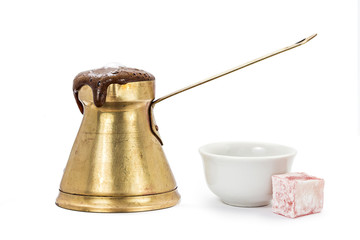 Coffee is seething outside from the traditional old brass coffee pot with traditional coffee cup and turkish delight, lokum, isolated on white
