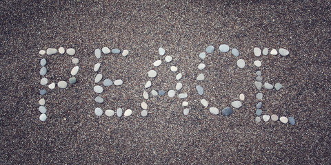 'Peace' word on the sand. Written with pebbles. Aged photo.