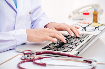 doctor typing information on the computer in office