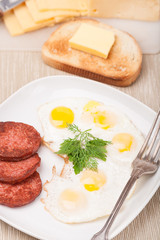 breakfast with fried eggs, sausage and toast on plate