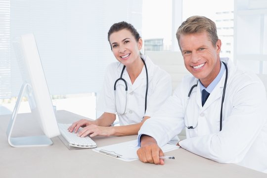Smiling female and male doctors looking at camera 