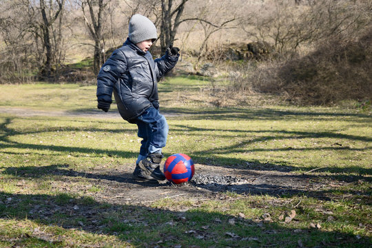 little boy 6-7 years hits the ball to score a goal