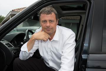 Attractive businessman gets into his car to go to work.