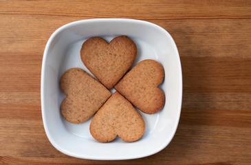 A white bowl with four heart-shaped homemade cookies inside