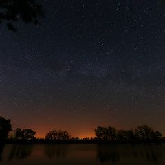 Fototapeta na wymiar Smooth surface of forest lake on a background of the night sky 