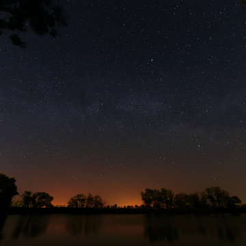 Smooth surface of forest lake on a background of the night sky 
