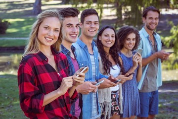 Happy friends in the park using their phones