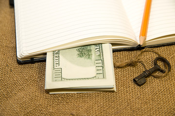 Opened notebook, pencil and money on the old tissue