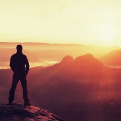 Hiker stand on the sharp corner of sandstone rock in rock empires park and watching over the misty and foggy morning valley to Sun. Beautiful moment the miracle of nature