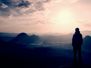 Hiker stand on the sharp corner of sandstone rock in rock empires park and watching over the misty and foggy morning valley to Sun.