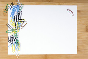 paper clips and blank paper on wooden background