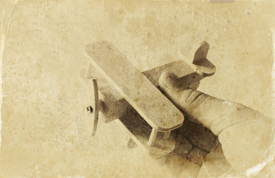 close up photo of man's hand holding wooden toy airplane