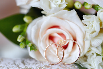 Gold wedding rings on a bouquet of flowers for the bride
