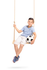 Relaxed boy holding football seated on a swing