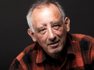 Obraz premium Portrait of senior man looking at camera on black background