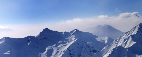 Panorama of snowy mountains in early morning fog