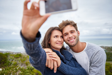 Fototapeta premium Young woman smiling at her boyfriend while taking a selfie