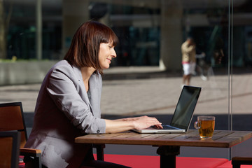 Happy businesswoman using laptop at cafe