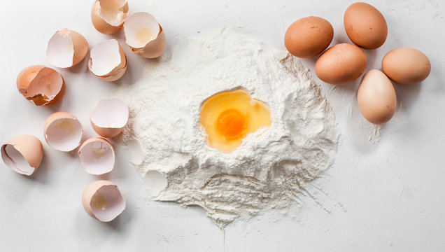 white background with eggs , shells and flour