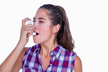 Pretty brunette woman using asthma inhaler 