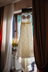 white bride dress hangs in front of the window