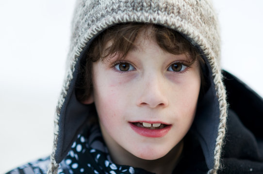 close up of an eight year old boy wearing a wooly winter hat 