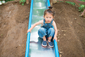 オーバーオールを着て滑り台で遊ぶ女の子