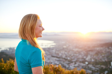 Young woman smiling as the sun rises over the city