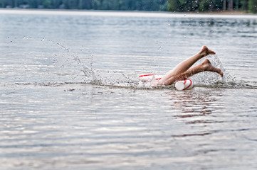 girls feet splashing the water as she dives into a lake