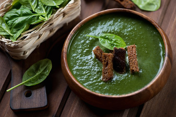 Freshly made spinach cream soup in a wooden bowl, close-up