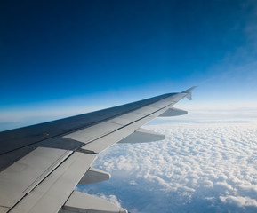 Obraz premium Wing of airplane flying above the clouds in the sky