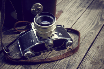 Old retro camera and belt bag (leather case) on vintage wooden boards abstract background