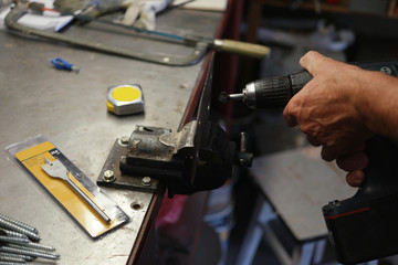 Laborer using an electric drill while metalworking