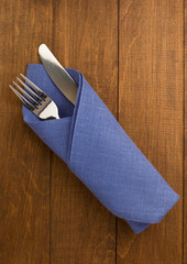 knife and fork at napkin on wood