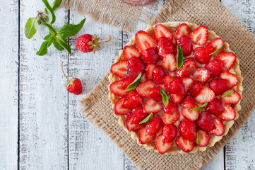 Tart with strawberries and whipped cream decorated with mint leaves