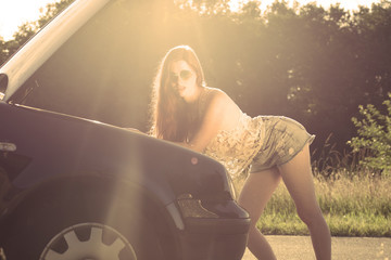 Sexy young redhead woman repairing a broken car