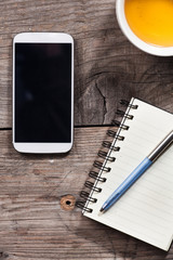 brown desk with mobile phone , notepad and tea