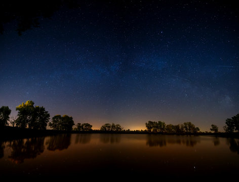 Smooth surface of forest lake on a background of the night sky a