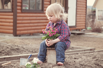 Little girl planting and watering flowers in garden