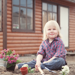 Little girl planting and watering flowers in garden