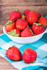 fresh strawberries in a bowl with napkin on old wooden background