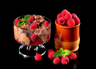 Chocolate ice cream with fresh raspberries isolated on a black b
