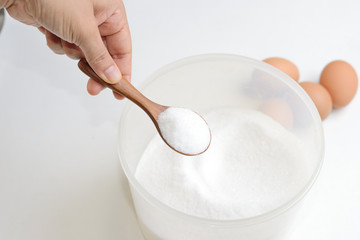 a wooden spoonful of sugar with aggs as background