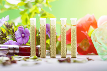 small glass tubes with homeopathy globules, syringe and flowers