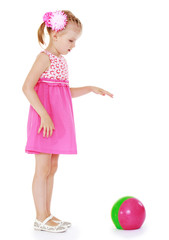 Adorable blonde girl in short summer dress playing ball while st