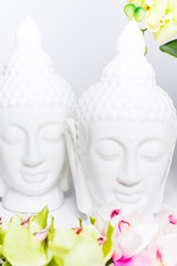 Two decorative statues of Buddha with orchids