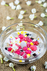 Thai dessert, Ruby framework sprinkled with corn with coconut milk and jasmine on hemp background. 