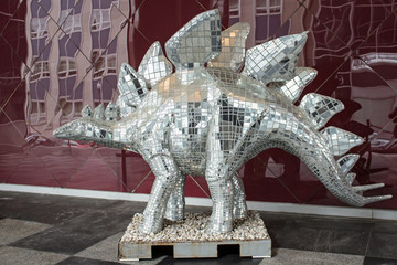 Mirrored Dinosaur - Mirrored Dinosaur Standing On a Black and White Checkered Floor in Front of a Reflective Red Tile