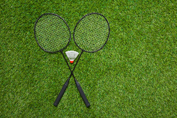Crossed badminton rackets with white shuttlecock 